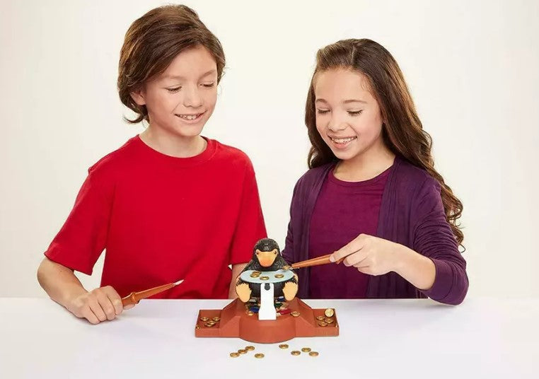 Two children playing with a toy Niffler  on a white background