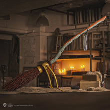 Wizarding broomstick with gold handle in a cozy, dimly lit room.
