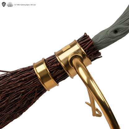 Close-up of a broom with gold handle and bristles on a white background