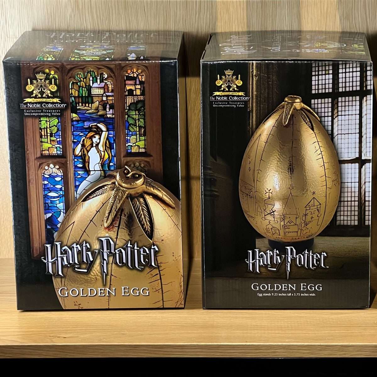 Two Harry Potter Golden Egg collectibles in their packaging on a wooden surface.