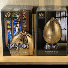 Two Harry Potter Golden Egg collectibles in their packaging on a wooden surface.