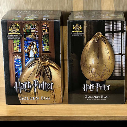 Two Harry Potter Golden Egg collectibles in their packaging on a wooden surface.