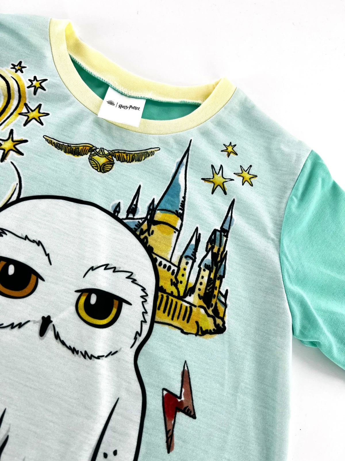 Children's shirt with owl and castle design on a light blue background