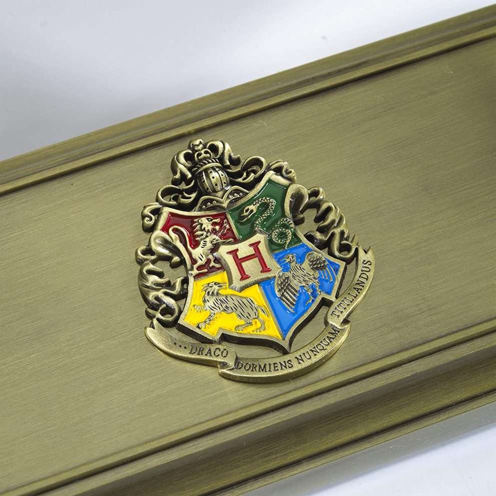 Gold Hogwarts crest on a wooden surface