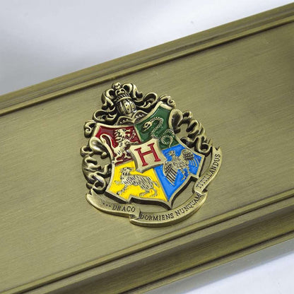 Gold Hogwarts crest on a wooden surface