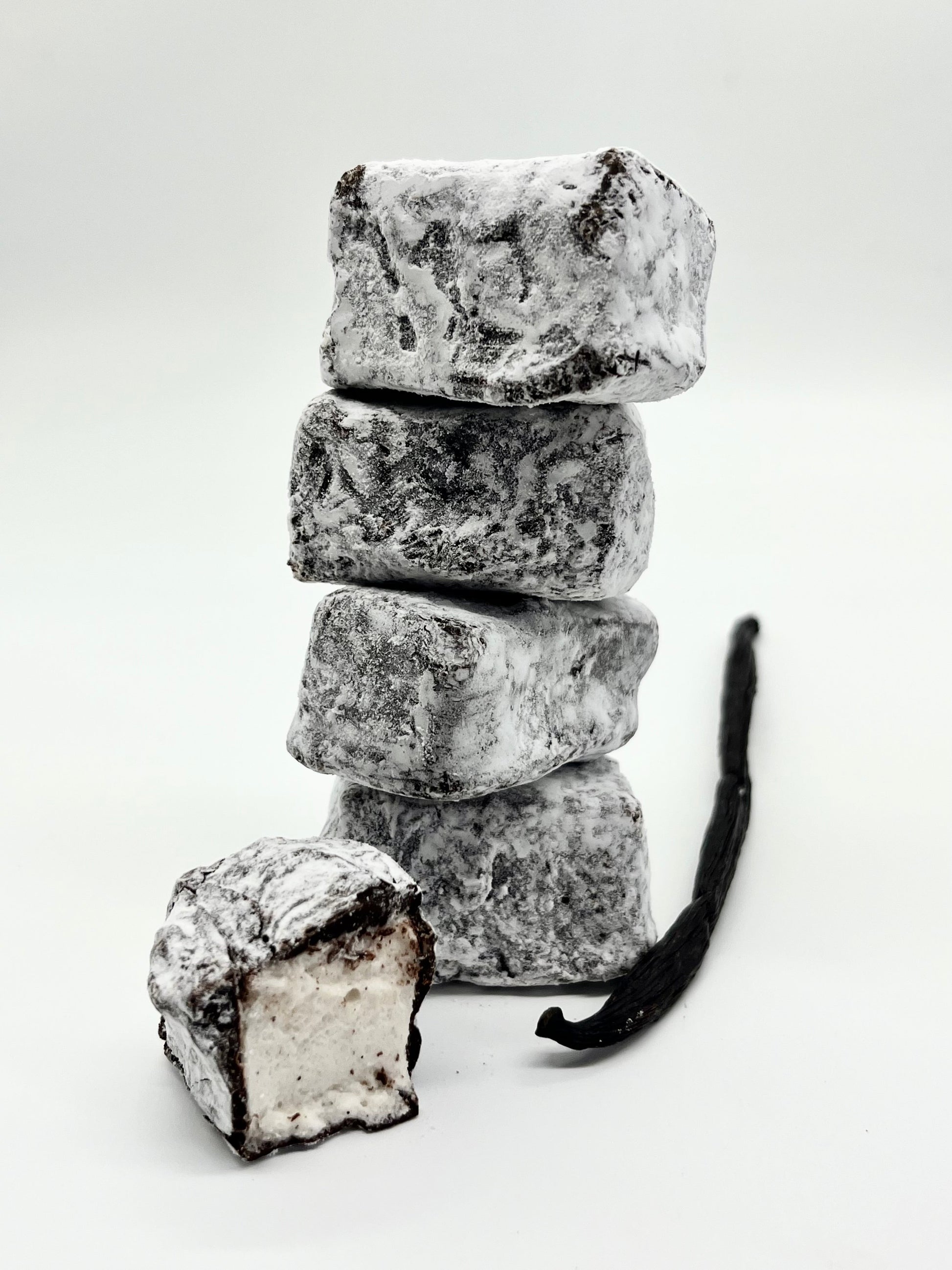 Stack of powdered sugar-covered vanilla ice cream bars with a vanilla bean on a white background