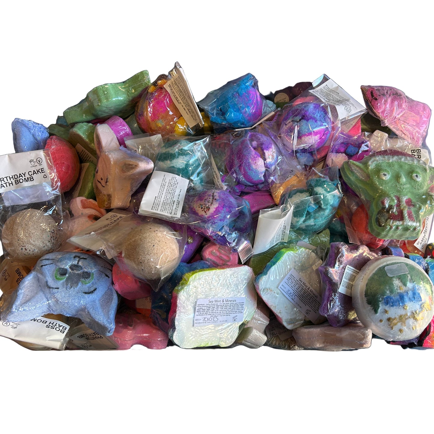 Assorted colourful bath bombs in a clear plastic container on a white background