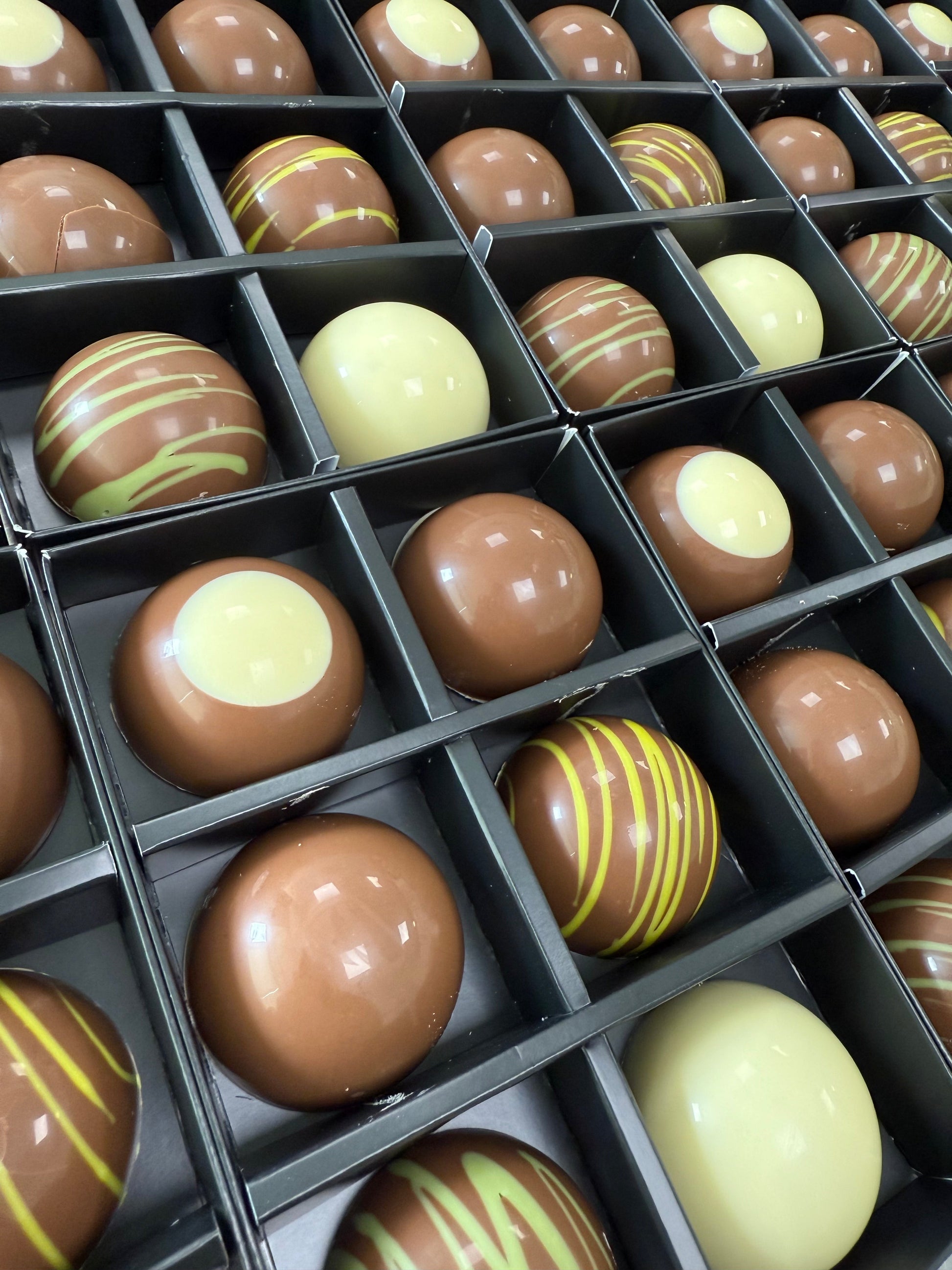 Assorted chocolates in a box with different colours and patterns.