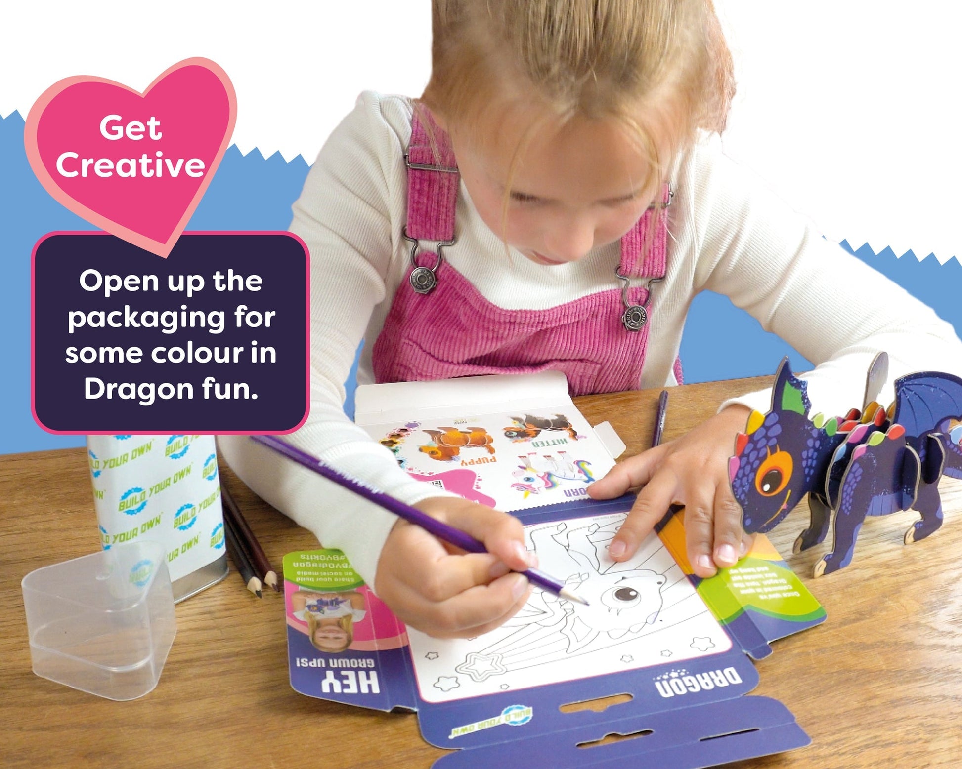Child coloring a dragon with a coloring book and crayons on a table.