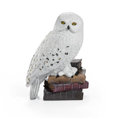 White owl Hedwig on a stack of books against a white background