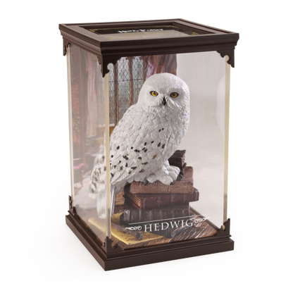 Model of a snowy owl in a glass display case with 'Hedwig' branding.