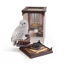 Model of a snowy owl Hedwig on books with a Harry Potter-themed box in the background