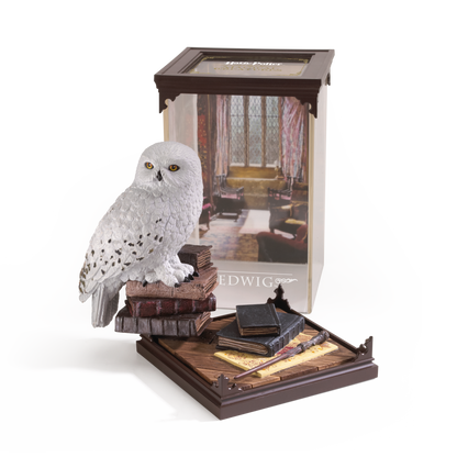 Model of a snowy owl Hedwig on books with a Harry Potter-themed box in the background