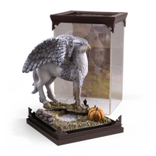 Statue of a winged creature Buckbeak on a decorative base with a clear display case.