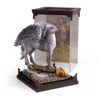 Statue of a winged creature Buckbeak on a decorative base with a clear display case.