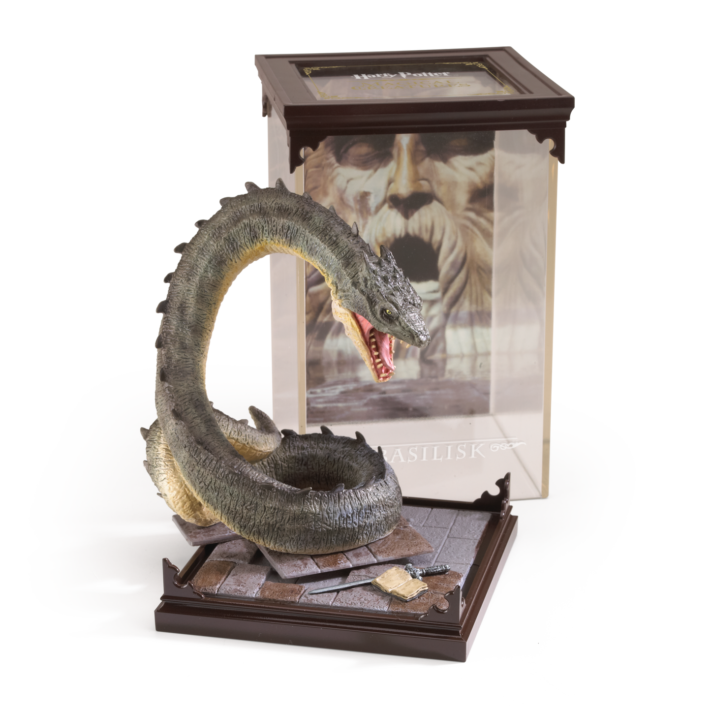 Basilisk figurine on a stand with a book featuring a character's face in the background