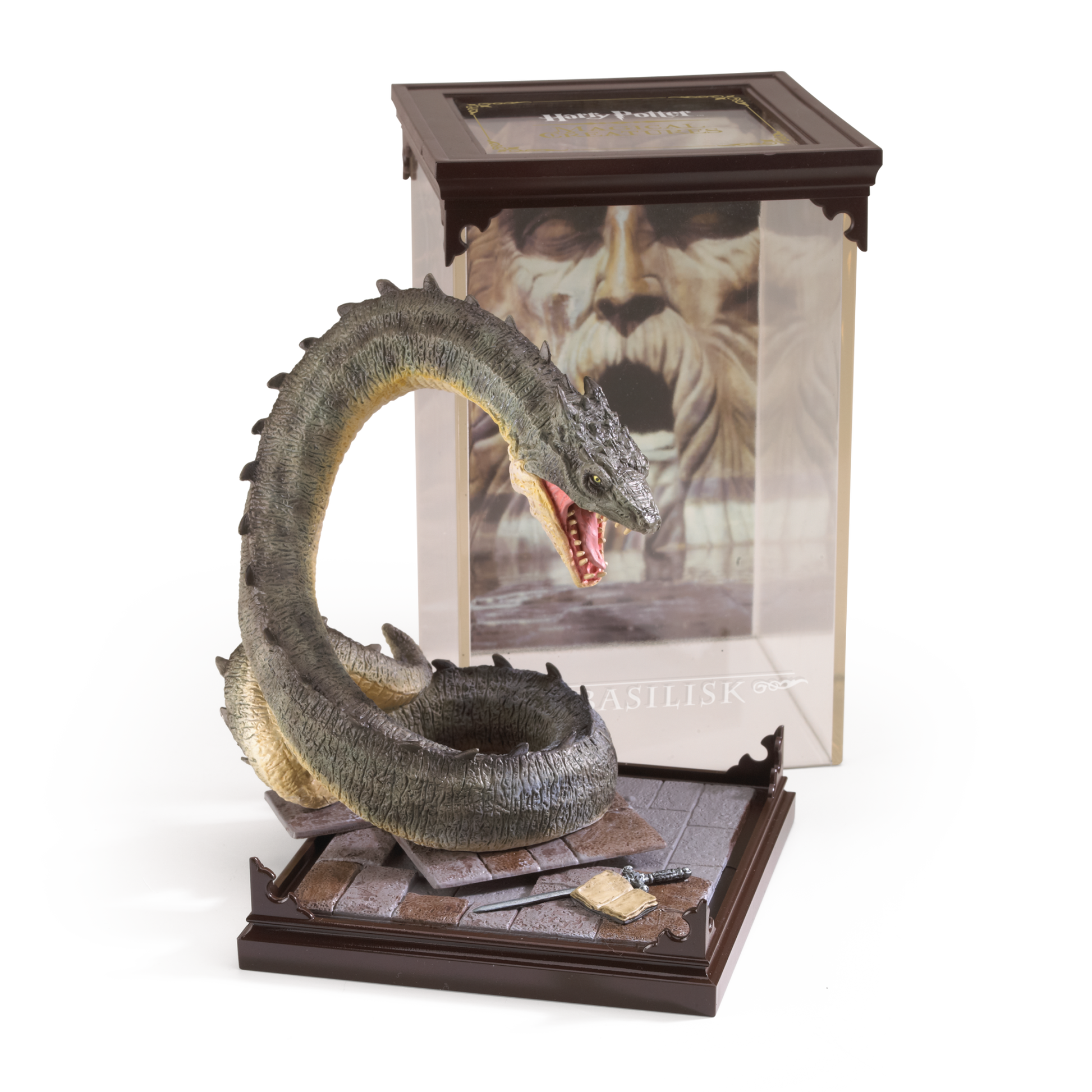 Basilisk figurine on a stand with a book featuring a character's face in the background