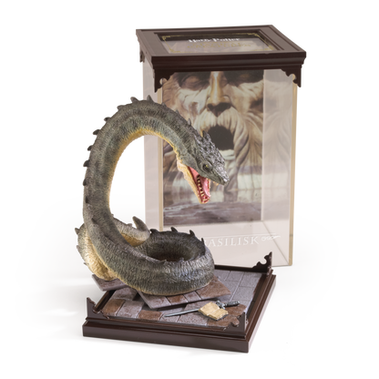 Basilisk figurine on a stand with a book featuring a character's face in the background