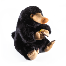 Plush toy Niffler holding a yellow flower on a white background