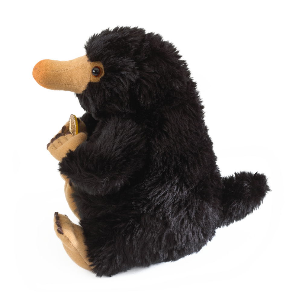 Plush Niffler toy holding a lodge on a white background