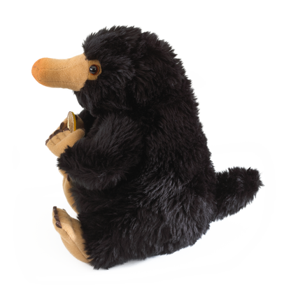 Plush Niffler toy holding a lodge on a white background