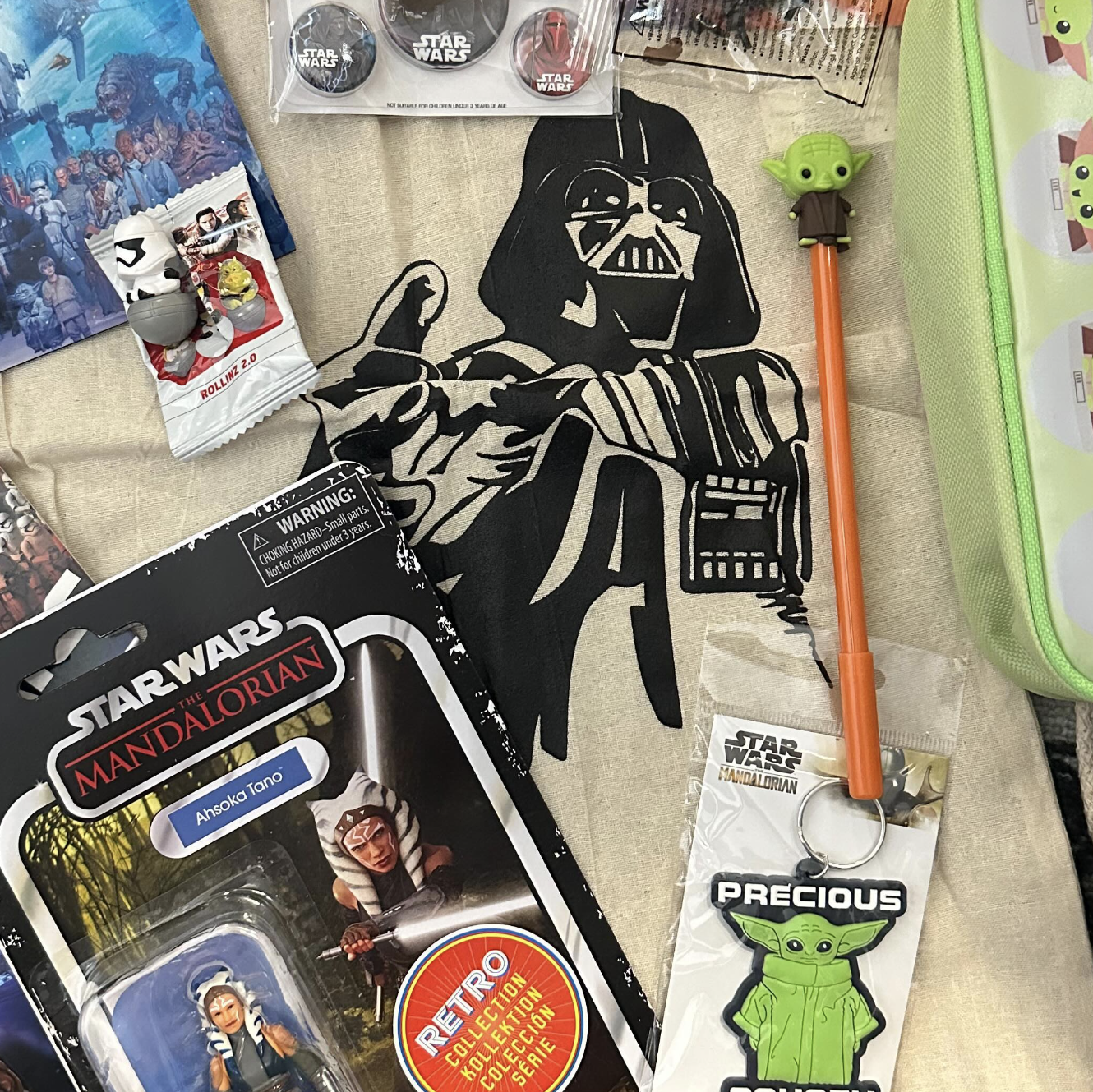 Collection of Star Wars-themed merchandise including action figures, keychains, and a pencil on a textured surface.