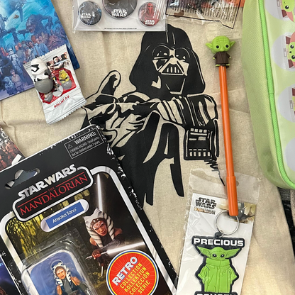Collection of Star Wars-themed merchandise including action figures, keychains, and a pencil on a textured surface.