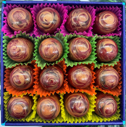 Marbled chocolate truffles in colourful wrappers arranged in a box.