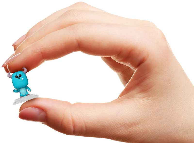 Small blue creature figurine held between fingers against a white background