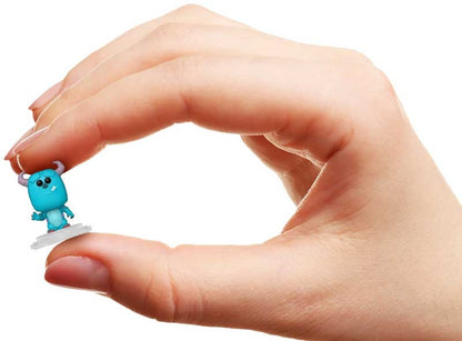 Small blue creature figurine held between fingers against a white background