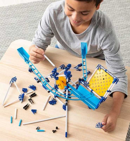 Child playing with a marble run toy set on a wooden table.