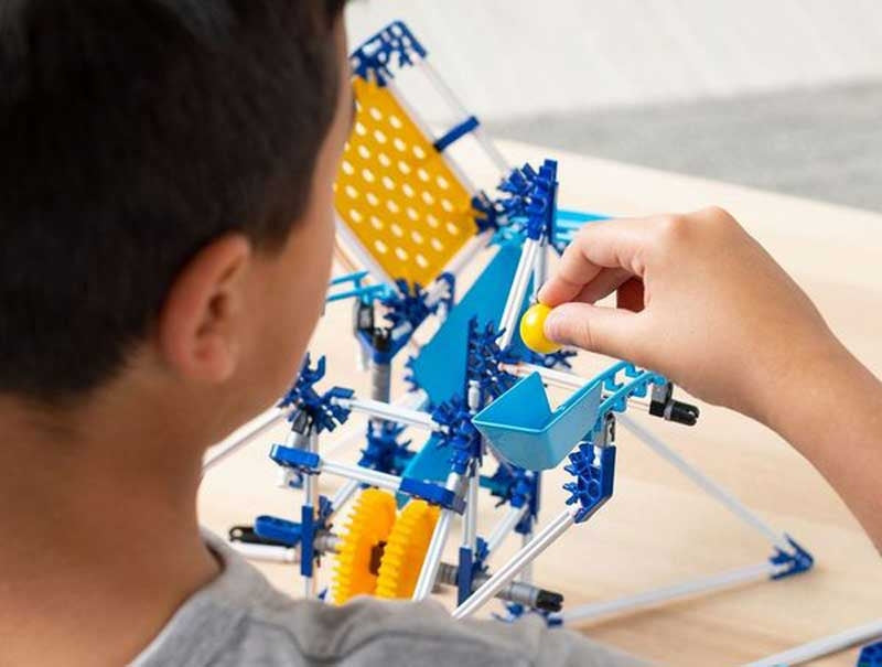 Child playing with a marble run toy set on a table