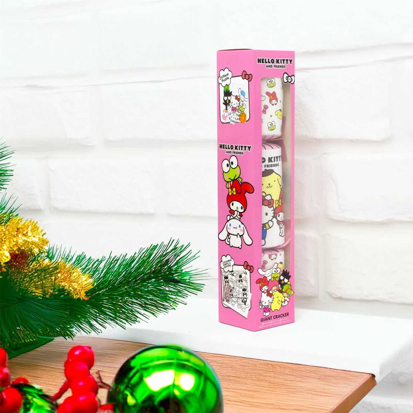 Pink box of Hello Kitty and friends ornaments on a white surface with Christmas decorations.
