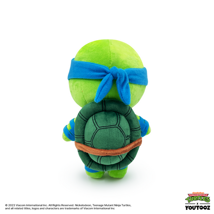 Plush toy of a green turtle with a blue headband on a white background